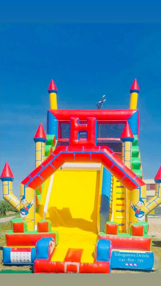 Barvito napihljivo igralo grad z Disney motivi – čarobna atrakcija za pravljične otroške zabave in rojstne dneve.