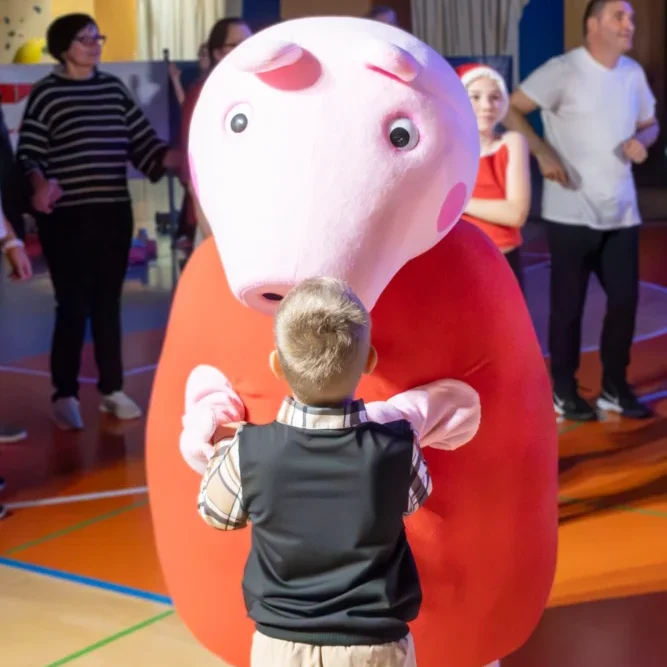 Oseba v kostumu Pujske Peppe med animacijo za otroke – priljubljen lik, ki poskrbi za smeh in veselje na zabavi.